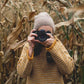 woman taking a picture wearing a yellow wool jumper